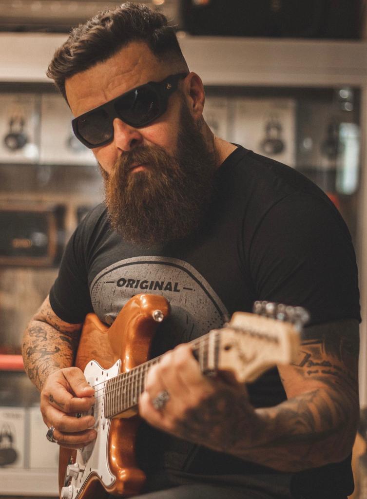 Homem de barba tocando guitarra